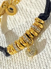 Juicy Couture Rhinestones pave pendant with Gold tone high gloss beads on black cord accent.