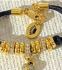 Juicy Couture Rhinestones pave pendant with Gold tone high gloss beads on black cord accent.