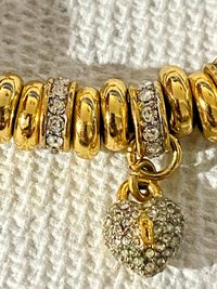 Juicy Couture Rhinestones pave pendant with Gold tone high gloss beads on black cord accent.