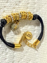 Juicy Couture Rhinestones pave pendant with Gold tone high gloss beads on black cord accent.