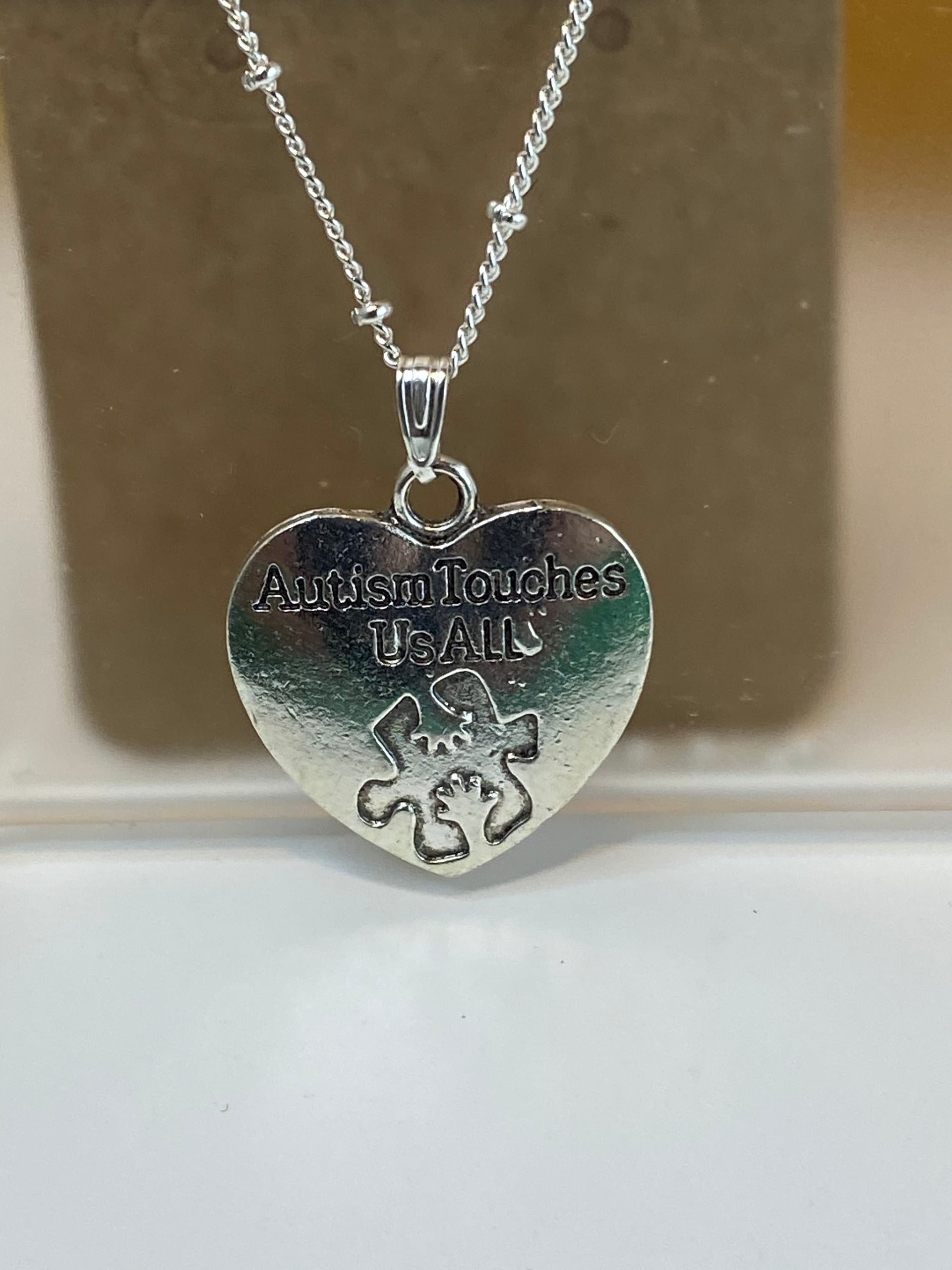 Silver necklace with Autism awareness message