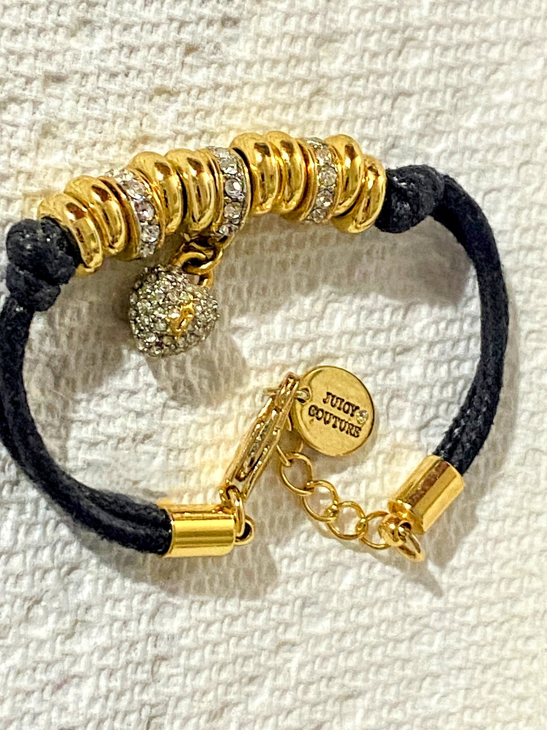 Juicy Couture Rhinestones pave pendant with Gold tone high gloss beads on black cord accent.