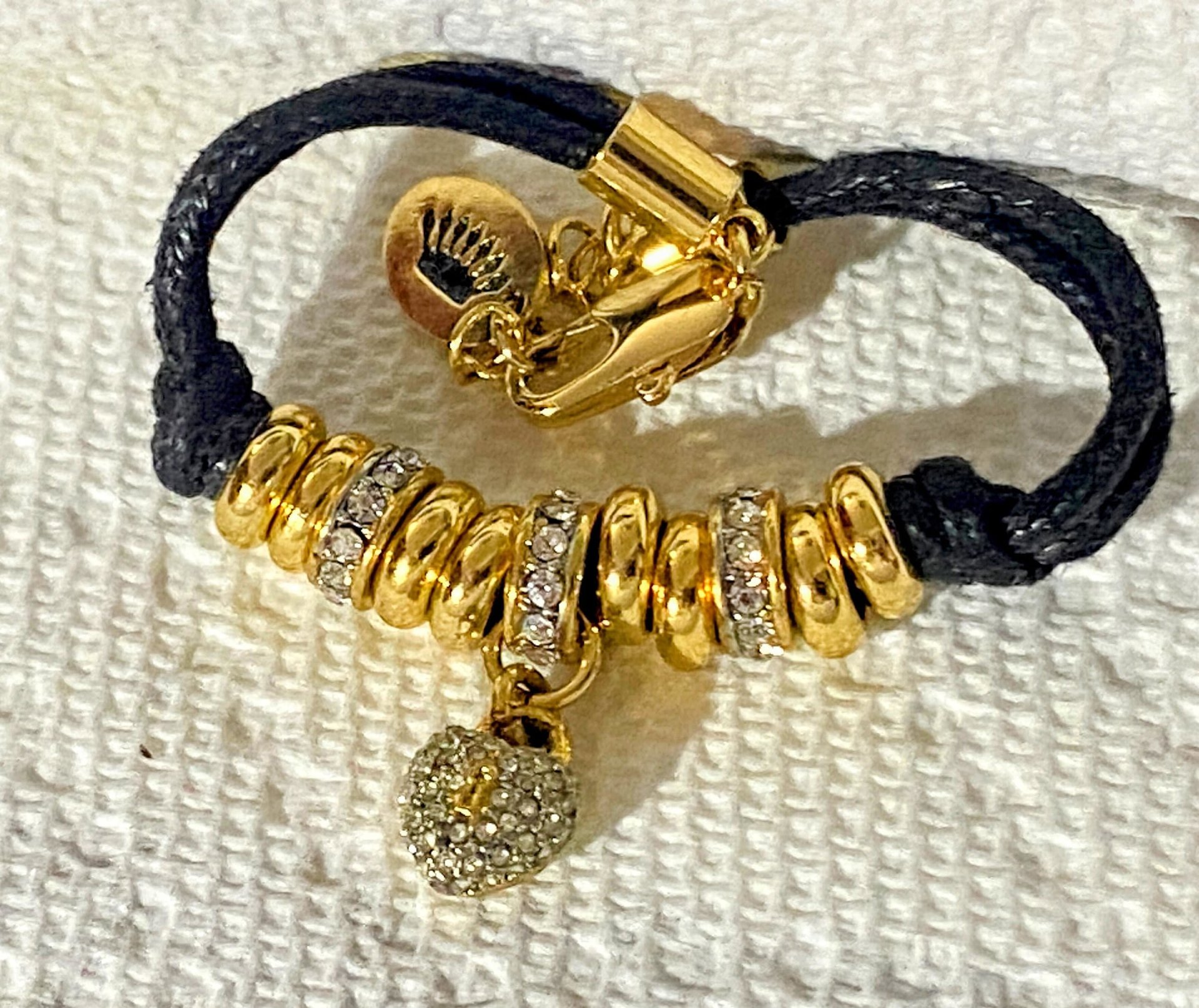 Juicy Couture Rhinestones pave pendant with Gold tone high gloss beads on black cord accent.